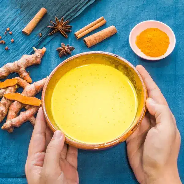 a person holding a bowl of yellow turmeric milk 