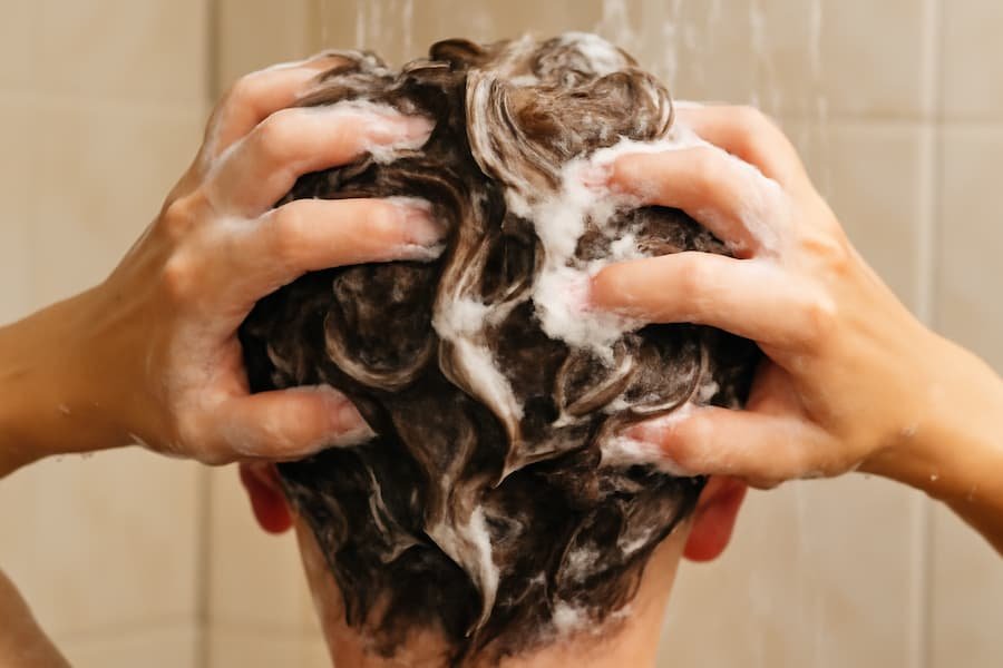 Washing out water-based hair wax with shampoo under a shower